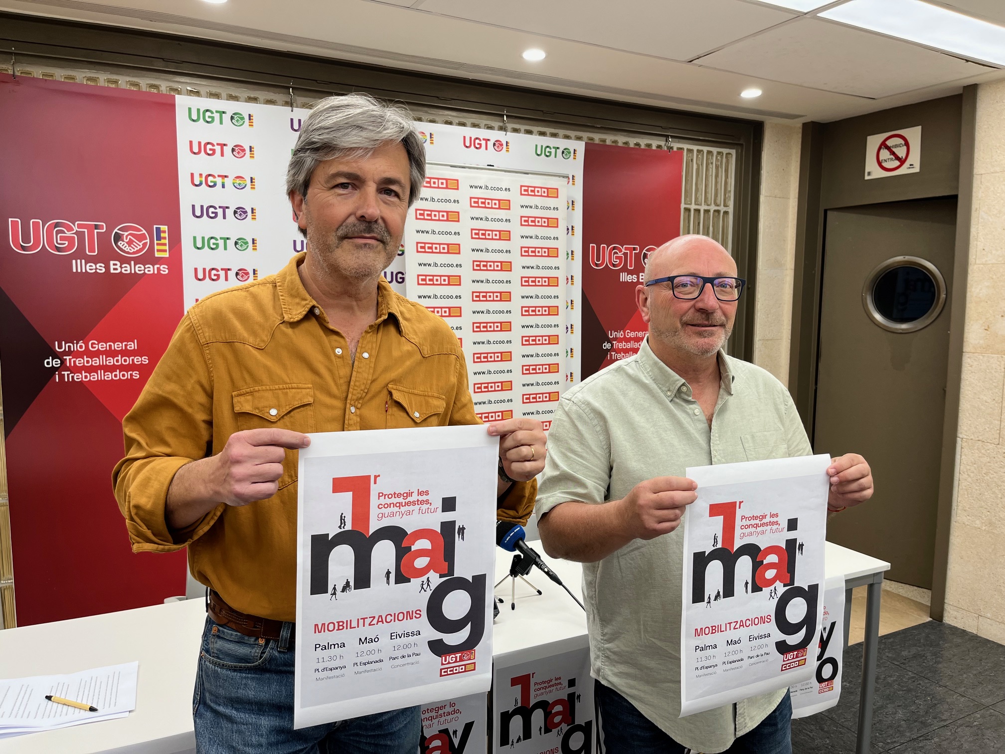 Muestran el cartel del Primero de Mayo, el secretario general de UGT, Pedro Homar, y el de CCOO, José Luis García Vidal. 