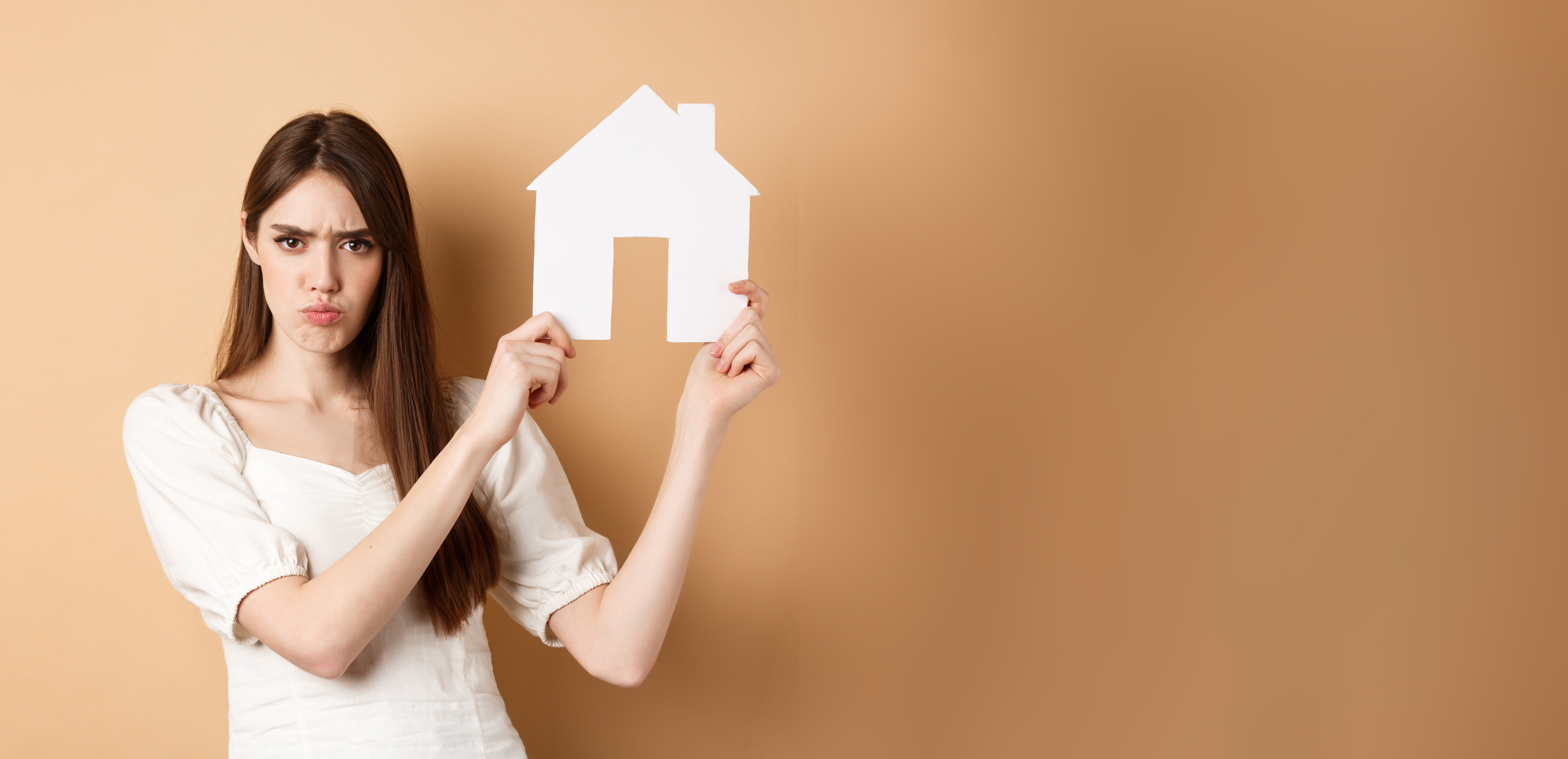 Imagen de una chica enfadada que porta la foto de una vivienda